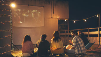 Friends watching a movie on a building rooftop terrace Host a movie night
